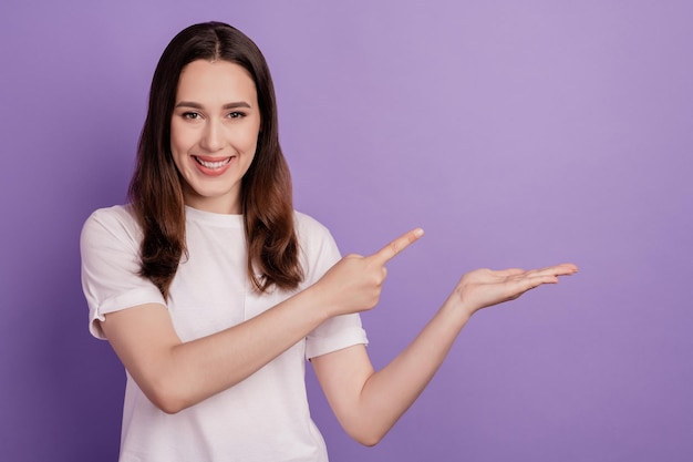 De foto van een jong mooi meisje geeft aan dat de aanbieding van het vingerpromo-object wordt geïsoleerd over een violette kleurachtergrond