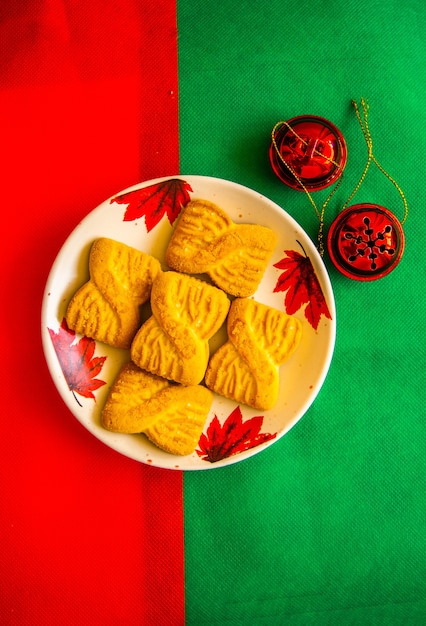 De foto van een stapel koekjes of zandkoekjes op het bord met rode belletjes. nationale koekjesdag achtergrond. kerstontbijt voor de kerstman.