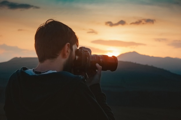 De fotograaf fotografeert de zonsondergang op de bergen