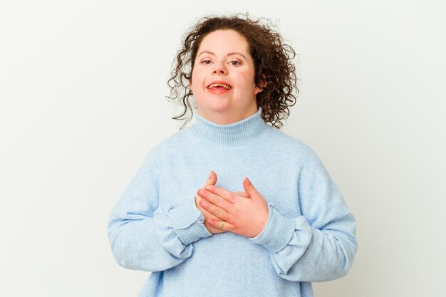 De geïsoleerde vrouw met het syndroom van Down heeft vriendelijke uitdrukking en drukt met de handpalm tegen de borst. Liefde concept