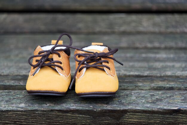 Foto de gele babylaarzen sluiten omhoog. kid schoenen op houten bankje in het park.