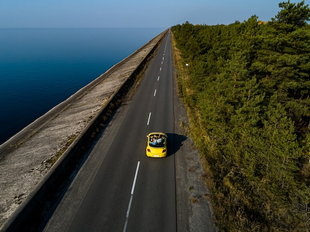De gele cabriolet rijden op de kustweg