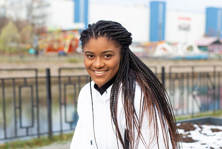 De gelukkige Afro-Amerikaanse vrouw in een park in een witte hoodie