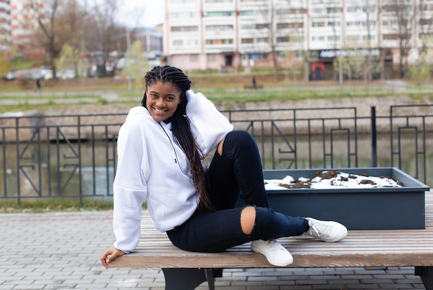 De gelukkige Afro-Amerikaanse vrouw in het park op een bankje