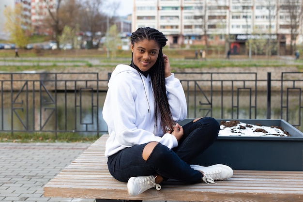 De gelukkige Afro-Amerikaanse vrouw in het park op een bankje