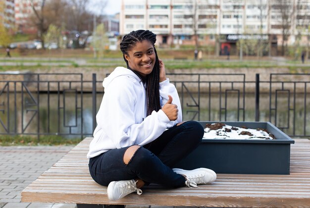 De gelukkige Afro-Amerikaanse vrouw in het park op een bankje