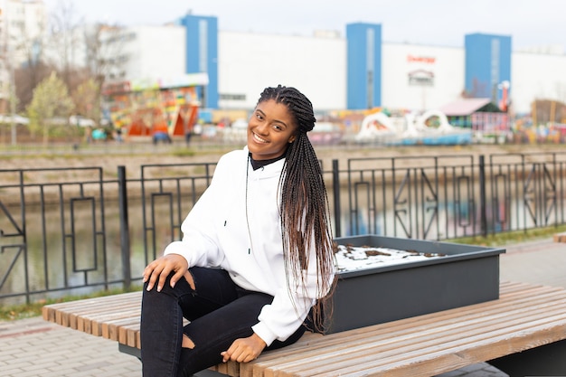 De gelukkige Afro-Amerikaanse vrouw in het park op een bankje