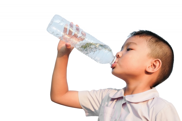 De gelukkige Aziatische jongen die van de kindstudent wat water van een plastic fles drinkt.