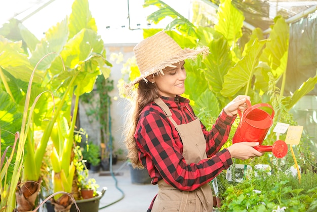 De gelukkige boer die de planten water geeft met kan in een groen bedrijfsconcept van de planten- en bloemenwinkel