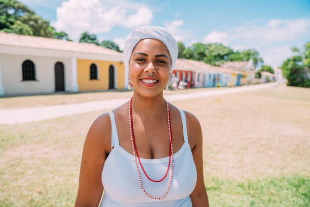 De gelukkige Braziliaanse vrouw kleedde zich in traditionele Bahiaanse klederdracht, in het historische centrum van Porto Seguro op de achtergrond