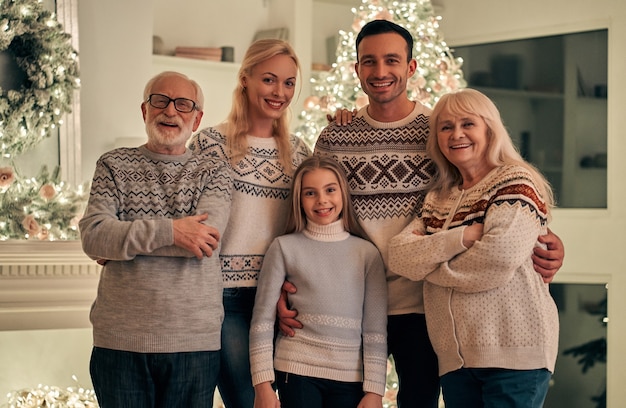 De gelukkige familie die op de achtergrond van de kerstboom staat