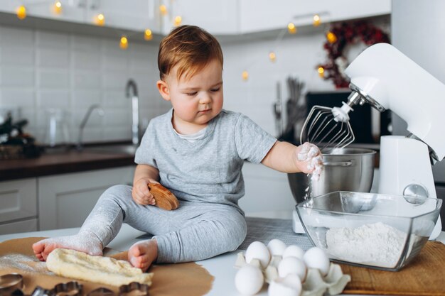 De gelukkige familie grappige jongen die het deeg voorbereiden, bakt koekjes in de keuken