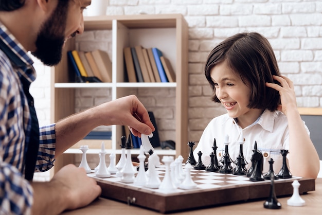 De gelukkige gebaarde vader speelt schaak met tienerzoon.