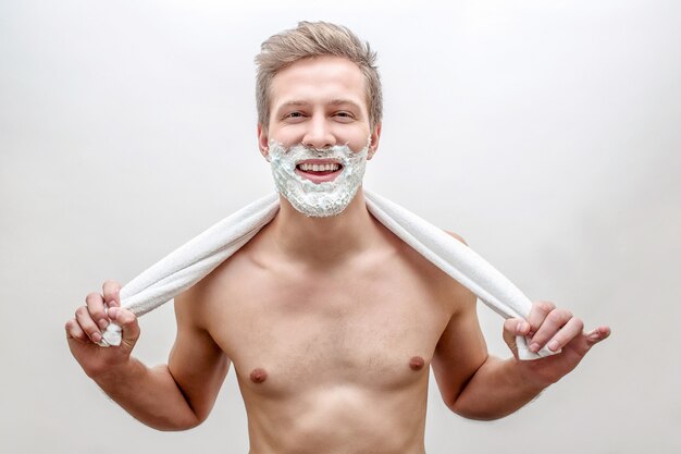 De gelukkige jonge mens met schuim op baard kijkt recht