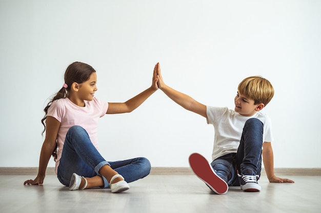 De gelukkige jongen en een meisje die op de grond zitten en gebaren maken