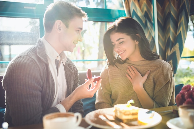 De gelukkige man doet een voorstel aan een vrouw in het restaurant