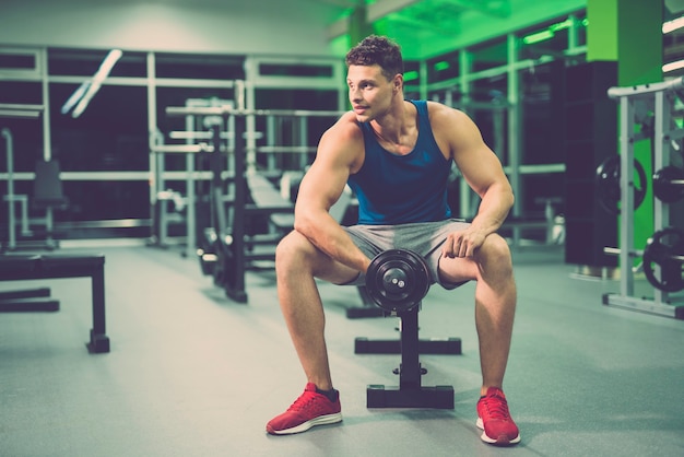 De gelukkige man doet oefening met een halter in de fitnessclub