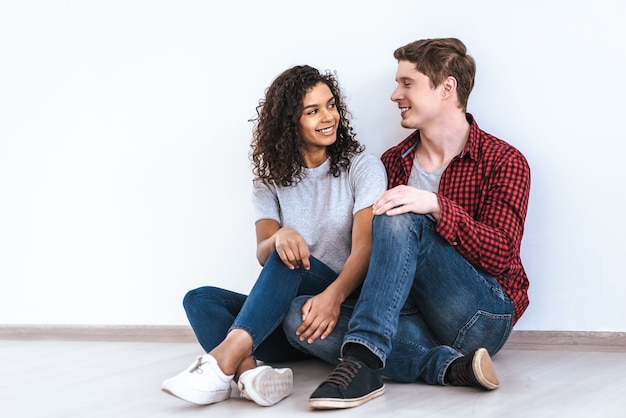 De gelukkige man en een vrouw die op de witte muurachtergrond zitten