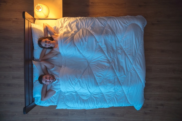 De gelukkige minnaars lagen op het bed. avond nacht tijd. uitzicht van boven