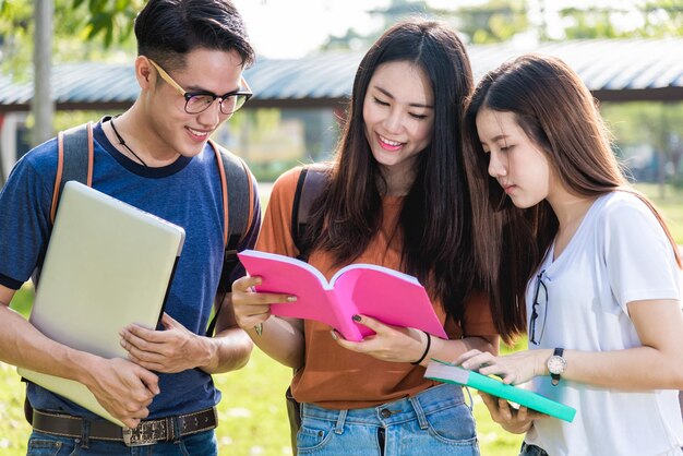 De gelukkige studenten van groepsvrienden die zich op de universiteit bevinden die schoolboek samen lezen