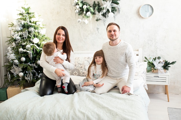 De gelukkige vader en de baby van de familiemoeder bij Kerstmisboom thuis