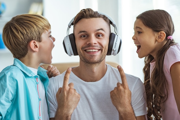 De gelukkige vader in koptelefoon spelen met een jongen en een meisje aan de balie