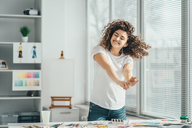 De gelukkige vrouw die bij de tafel danst met foto's