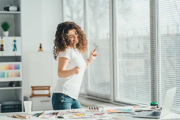 De gelukkige vrouw die bij de tafel danst met foto's