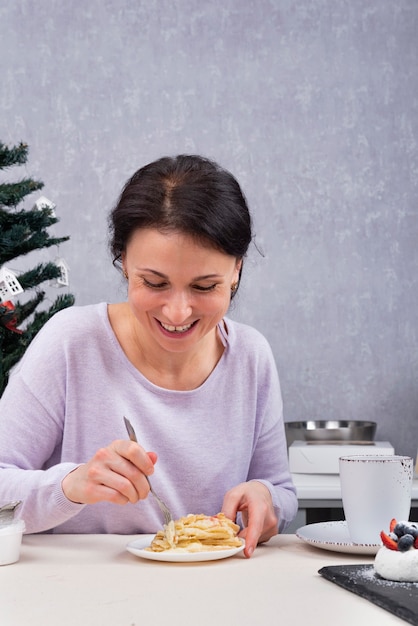 De gelukkige vrouw eet in haar keuken. Ontbijt met dessert.