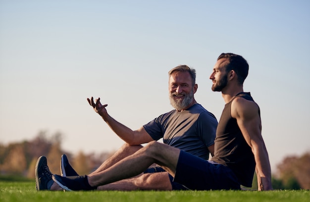 De gelukkige zoon en vader zittend op het gras