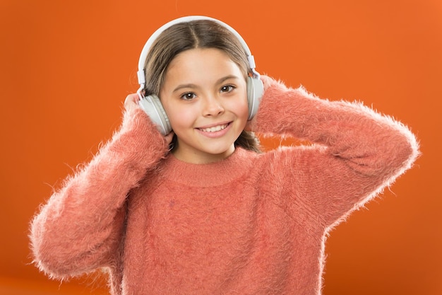 De gemakkelijkste manier om nieuwe muziek te vinden die lijkt op nummers waar je al van houdt. Meisje schattig klein kind draagt een koptelefoon luister muziek. Kid luister muziek oranje achtergrond. Aanbevolen muziek op basis van initiële interesse.