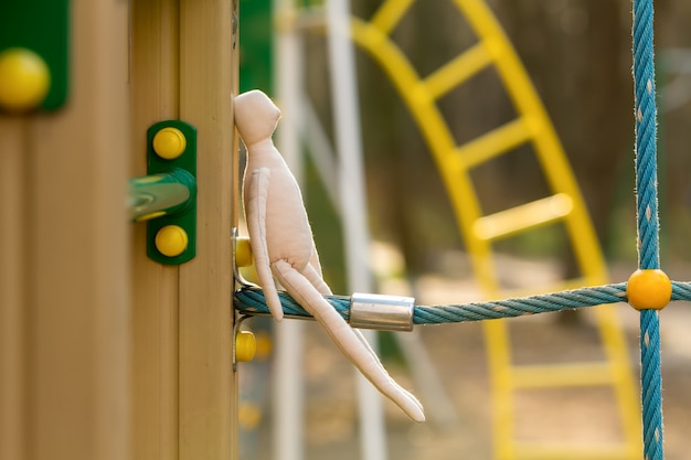 De genaaide gezichtsloze pop in het profiel zit aan een blauw touw, de constructie van een speeltuin.