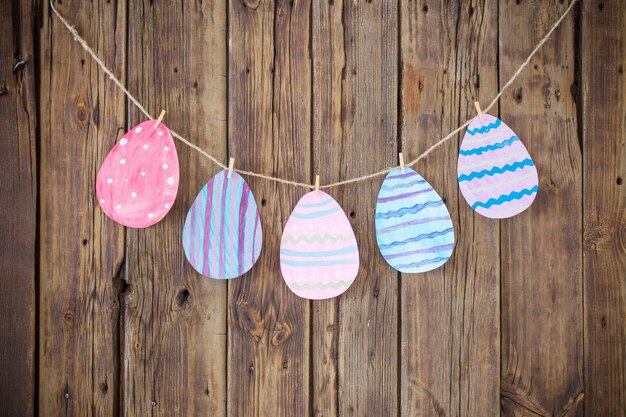 De geschilderde geschilderde eieren van Pasen hangen wasknijpers op achtergrond