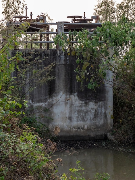 De gesloten betonnen sluizen van het station voor de controle van het water in het irrigatienetwerk in het vooraanzicht van het rijstveld met de kopieerruimte