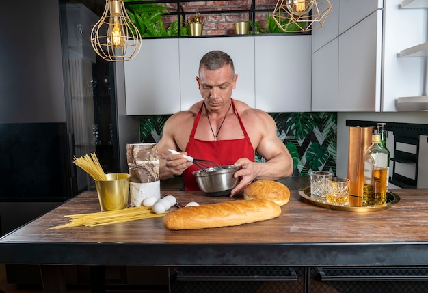 De gespierde man in de keuken bereidt een gerecht voor