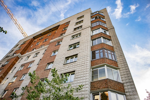 Foto de gevel van een modern woonbakstenen huis en de giek van een bouwkraan het concept van woningbouw en vastgoedinvesteringen