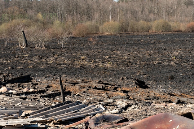 De gevolgen van een bosbrand De overblijfselen van een uitgebrand oud houten huis in Oekraïne As en verbrande dingen liggen op de grond