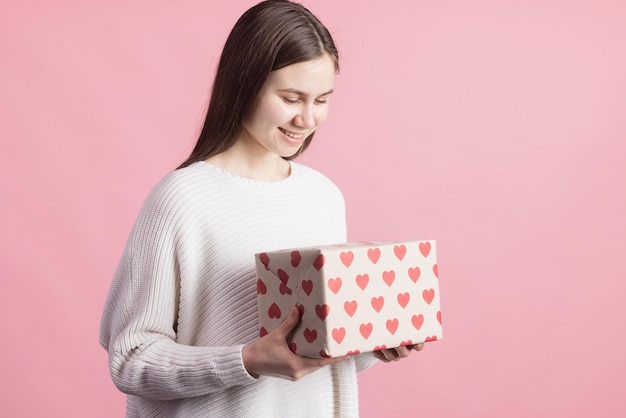 De gift van de meisjesholding met harten op de dagconcept van de roze achtergrondvalentijnskaart