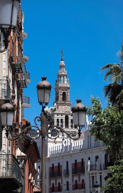 Foto de giralda de klokkentoren van de kathedraal van sevilla en traditionele lantaarnpaal in de voorgrond sevilla spanje