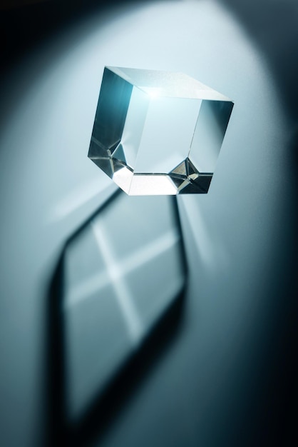 De glazen kubus werpt een schaduw op een blauwe achtergrond Abstracte compositie met transparant prisma en selectieve focus