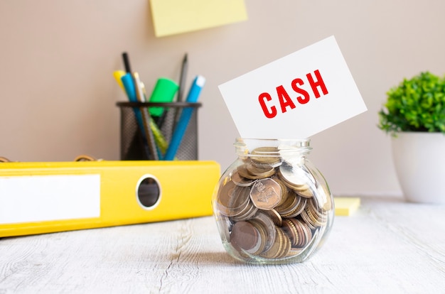 De glazen pot is gevuld met munten. Boven op de bank ligt een kaart met het opschrift CASH. Investeringsbudget.