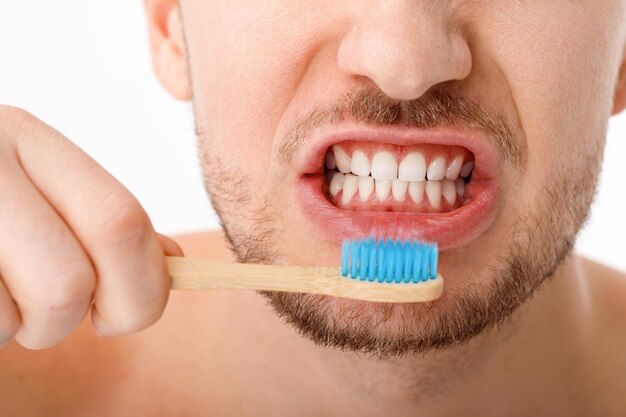 De glimlach van een jonge man in close-up Een man houdt een tandenborstel in zijn hand Het concept van mondverzorging