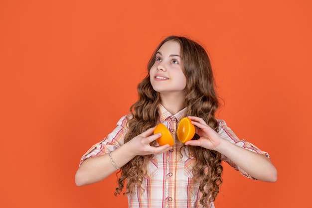 De glimlach van het tienermeisje houdt citroenfruit op oranje achtergrond