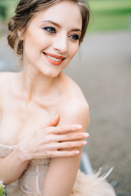 De glimlachende bruid in een mooie jurk legde haar hand op haar schouderportret