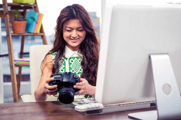 De glimlachende creatieve camera van de onderneemsterholding in het bureau