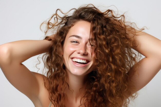 Foto de glimlachende jonge mooie vrouw houdt haar haar tegen haar gezicht terwijl ze lacht op een witte achtergrond