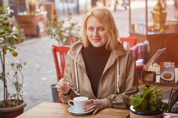 De glimlachende jonge vrouw ontspant in het straatcafé in Istanbul met een kopje koffie