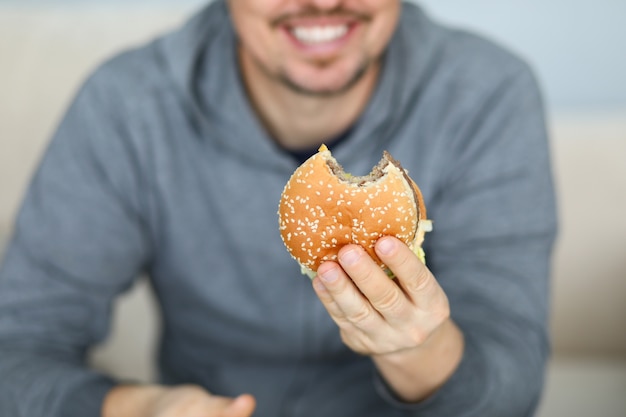 De glimlachende mens houdt verse hamburger in hand