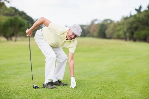 De glimlachende rijpe golfclub van de mensenholding terwijl het buigen op grasrijk gebied