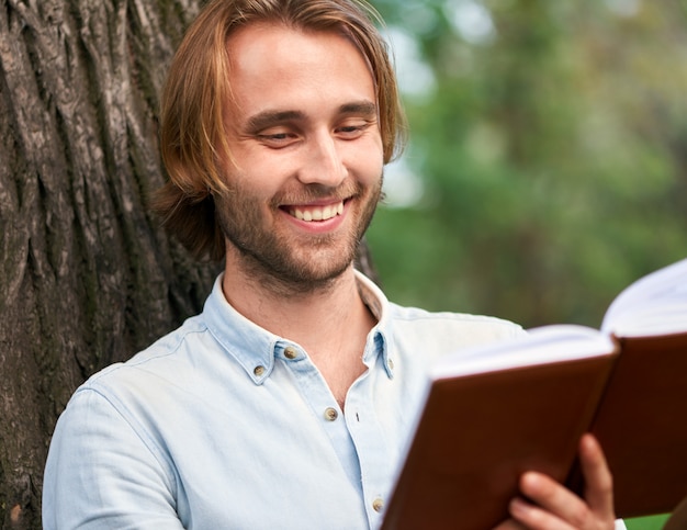 Foto de glimlachende student in park van campus las een boek